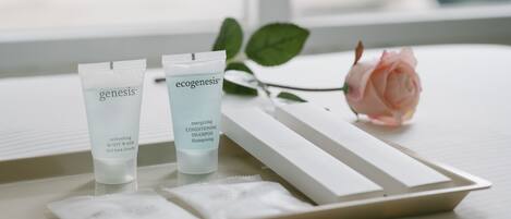 Dos tubos de productos para el cuidado de la piel, etiquetados como 'genesis' y 'ecogenesis', sobre una bandeja con una rosa y una servilleta.