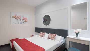 A modern bedroom with a bed, a bedside table, a mirror, and artwork on the wall.