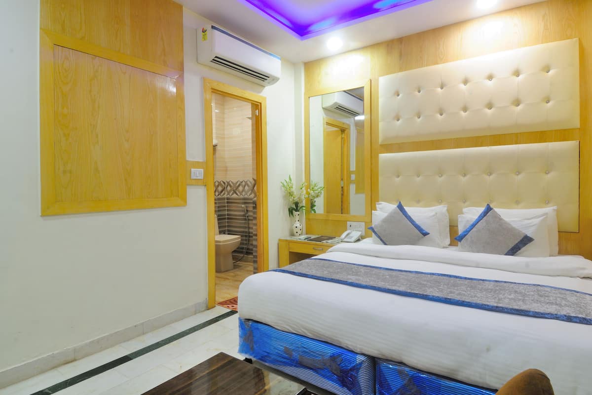 A hotel room with a large bed, a wooden headboard, a mirror, and a small bedside table.