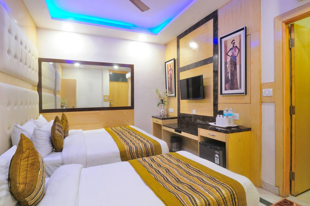 A hotel room with two beds, a desk, a TV, and a bathroom.