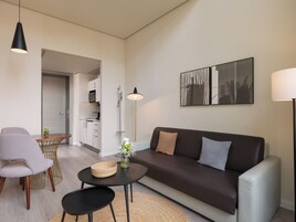 Una sala moderna con un sofá, dos sillones, una mesa de centro, una lámpara de pie y un comedor con mesa y sillas.