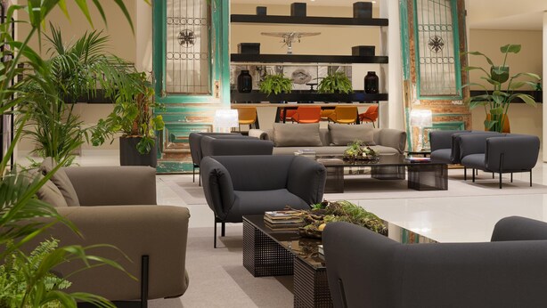 Una sala moderna con un sofá, sillones, una mesa de centro y plantas en macetas.