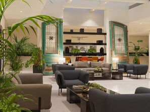 Una sala moderna con un sofá, sillones, una mesa de centro y plantas en macetas.