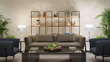 A modern living room with a sofa, two armchairs, a coffee table with a plant, and a shelving unit with decorative items.