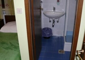 Una habitación pequeña con cama, lavamanos y piso de baldosas azules.