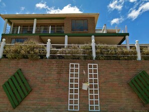 A two-story building with a balcony, a brick wall, and a hanging planter. - Amzee Bokmakierie Guest House (Mossel Bay)