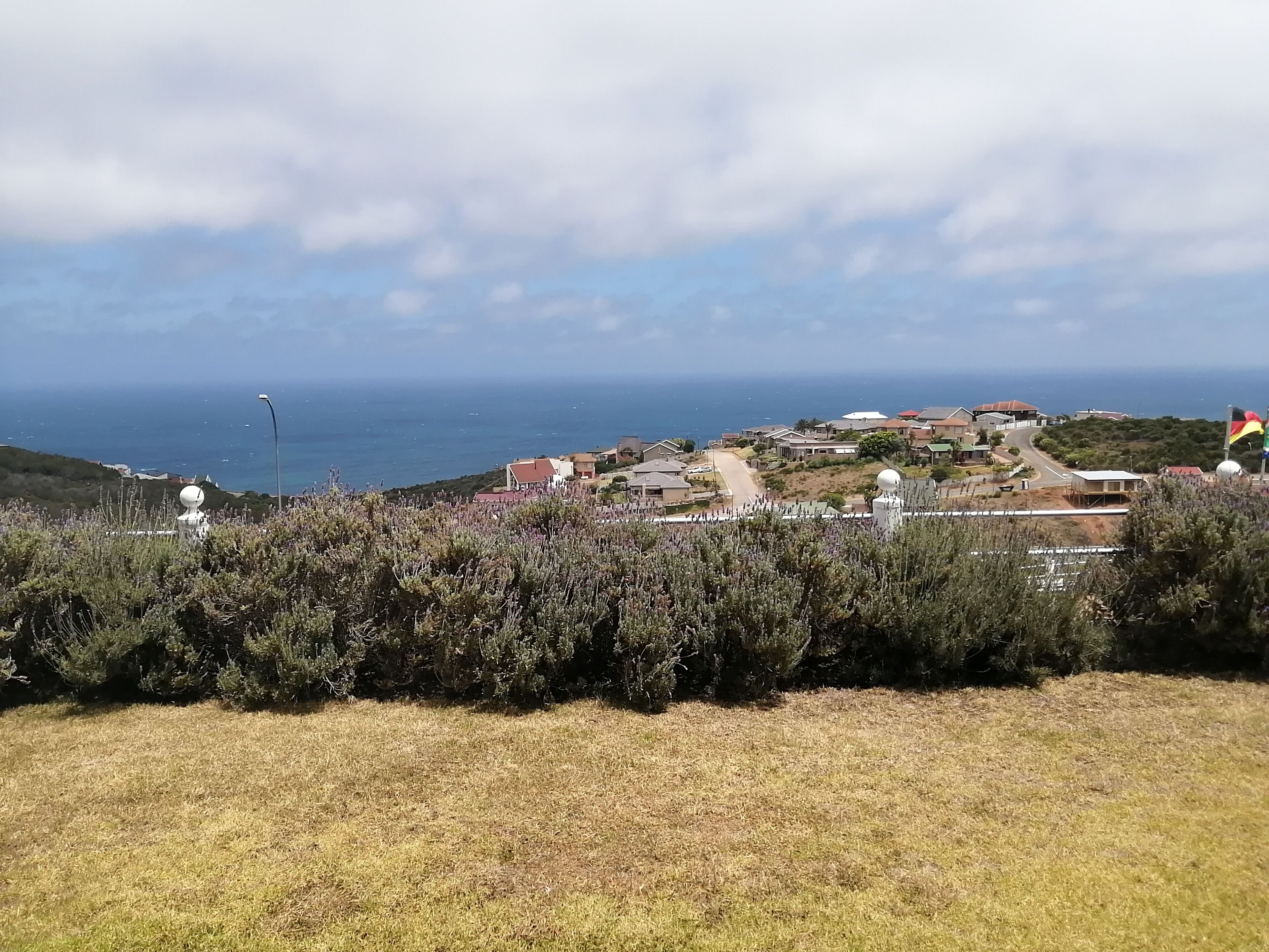 A coastal view with houses, a road, and a flag.