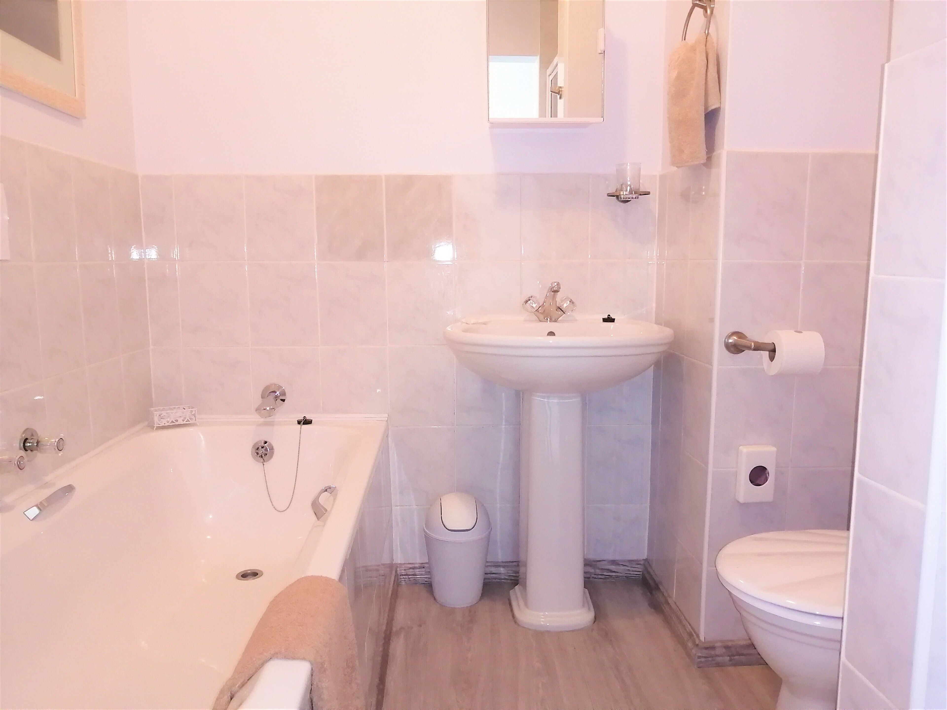 A bathroom with a bathtub, sink, toilet, and a mirror.