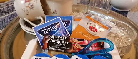 A tray with Tetley tea bags, Nescafe Classic coffee, Lakeland dairies whole milk, and a white cup with floral designs.