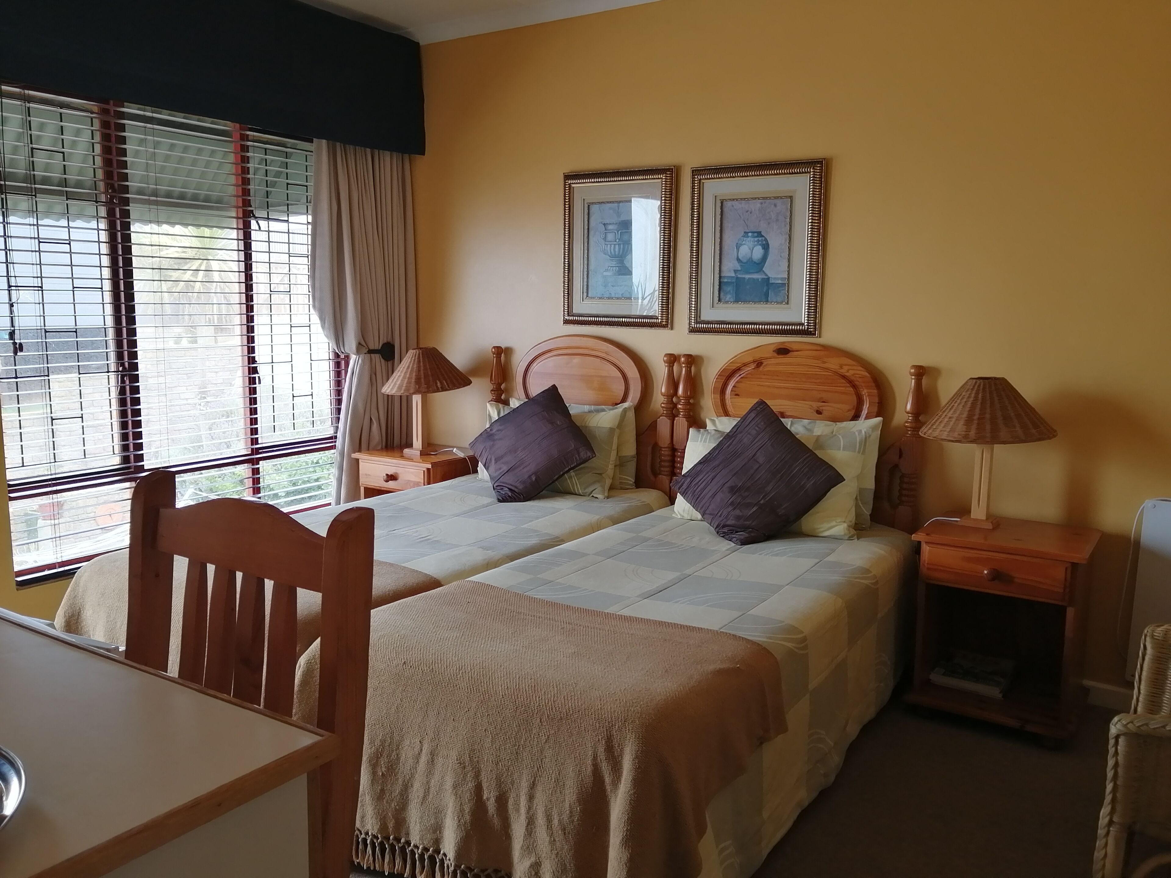 A double bed with a wooden headboard, two bedside tables with lamps, a chair, and a window with curtains.