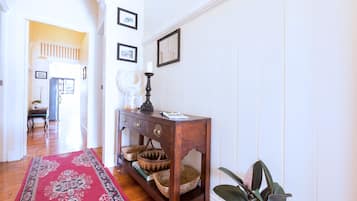 A hallway with a wooden console table, baskets, a red rug, and a potted plant.