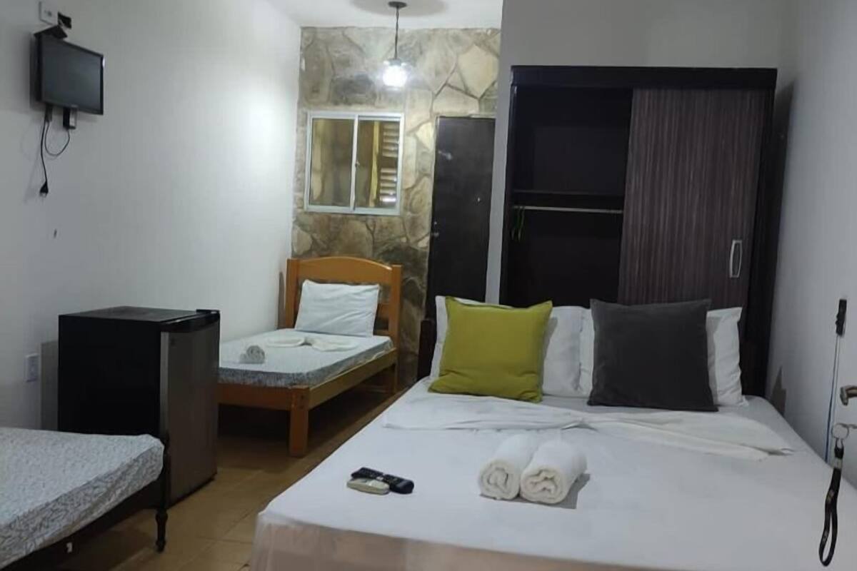 A hotel room with a bed, a desk, a television, and a wardrobe.