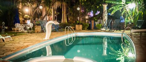 Een buitenzwembad, parasols bij het zwembad en ligstoelen