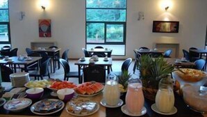 Comedor con mesas dispuestas para comidas, que incluye frutas, bebidas y platos.