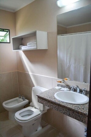 A bathroom with a toilet, bidet, sink, and a mirror.