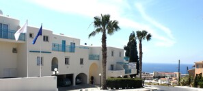 Un hotel con facciata bianca, balconi blu e un cartello che indica Sunny Hill Hotel Apartments.