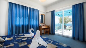 A hotel room with a bed, a desk, a chair, a balcony with a view, and a large window. - Sunny Hill Hotel Apartments (Chlorakas)