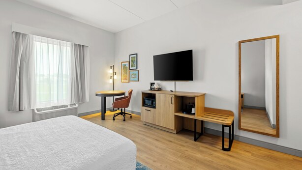 Een hotelkamer met een bed, bureau, stoel, televisie en kledingkast.