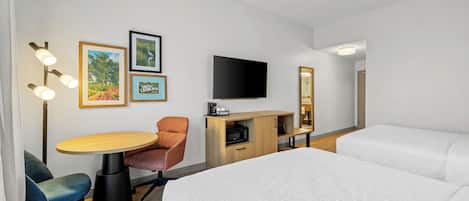 Ein Hotelzimmer mit einem Bett, einem Schreibtisch mit Stuhl, einem Fernseher und einem Spiegel.