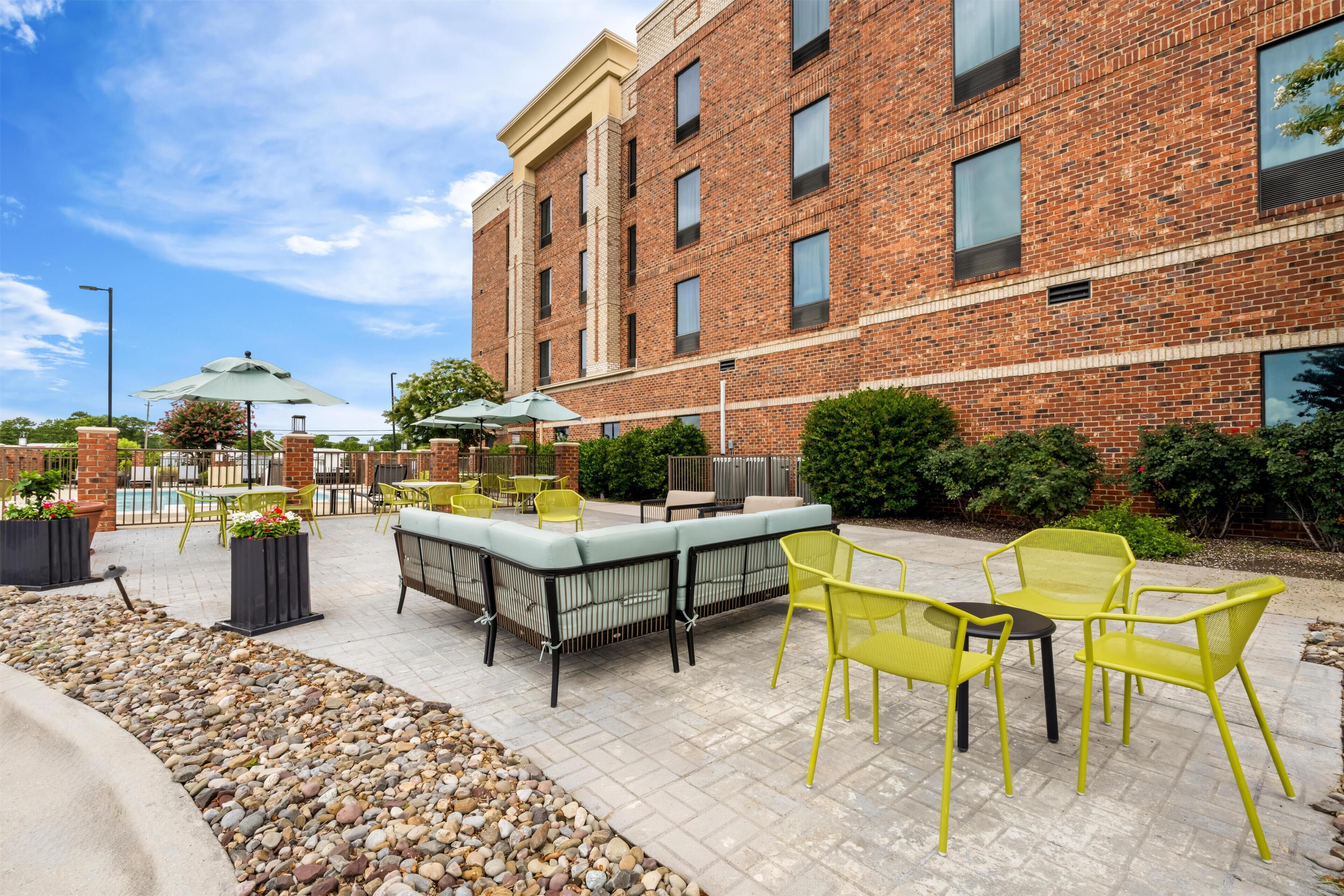 A brick building with outdoor seating and a pool.