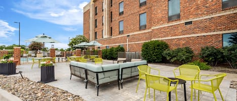 A brick building with outdoor seating and a pool.