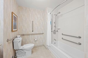 Une salle de bain équipée de toilettes, d’une douche et d’une baignoire. Des barres d’appui ont été installées pour plus de sécurité.