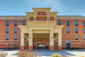 A brick building with a sign reading "Hampton Inn & Suites."