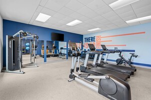 Un gimnasio con cintas de correr, máquinas de pesas y una pared de motivación.
