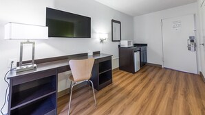 A hotel room with a desk, chair, flat-screen TV, microwave, and a door with a lock. - Motel 6 Warminster, PA (Warminster)