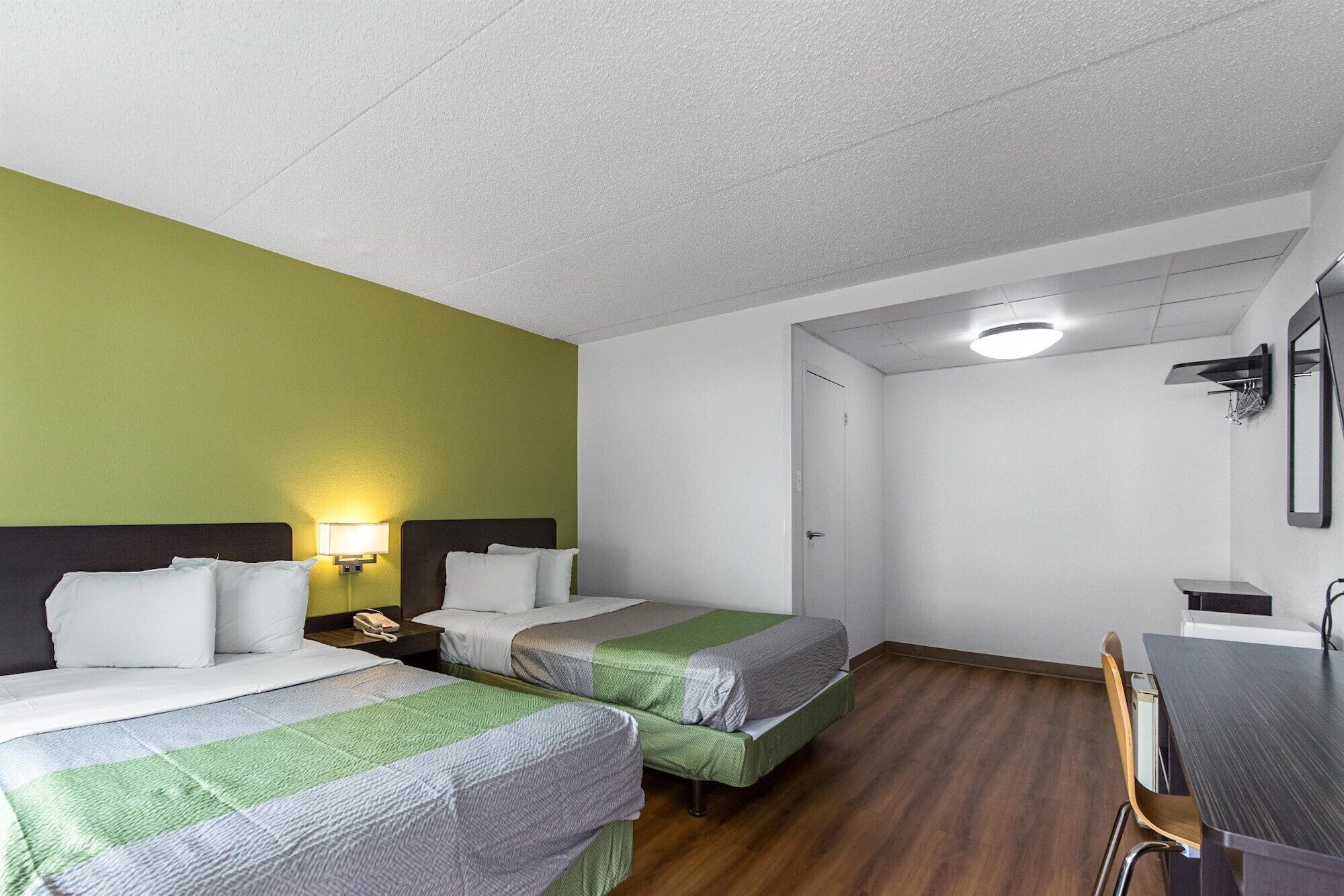 A hotel room with two beds, a desk, and a chair.