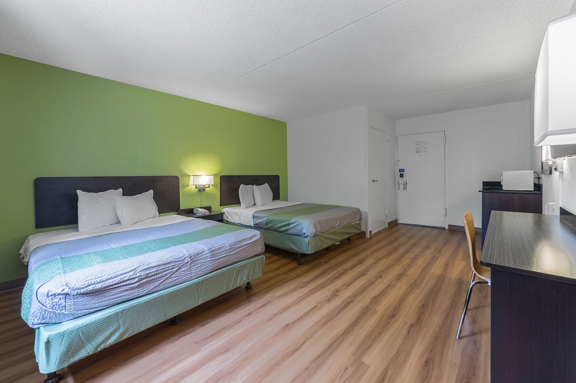 A hotel room with two beds, a desk, and a chair.