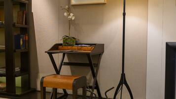 A room with a desk, chair, lamp, bookshelf, and a motorcycle.