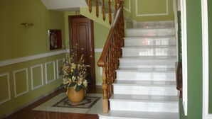 Una escalera con barandillas de madera y escalones blancos, que lleva a un piso superior.