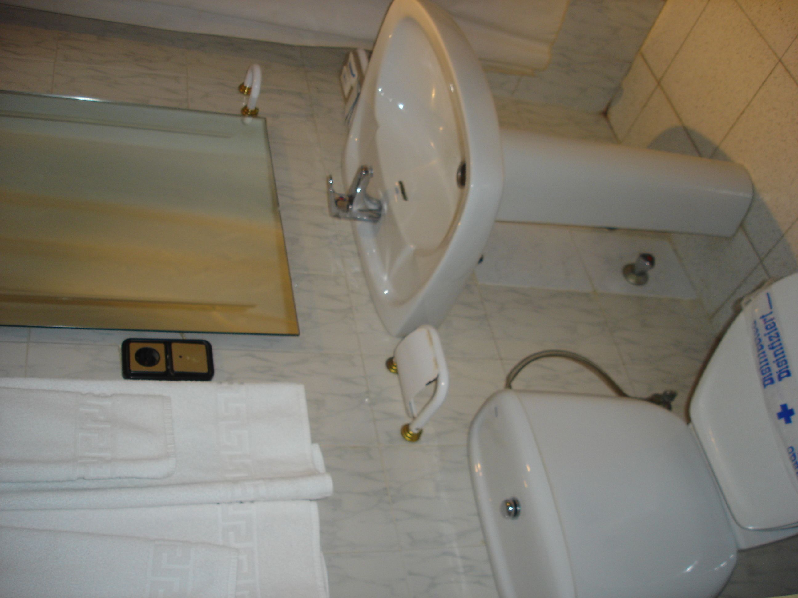 A bathroom with a sink, toilet, and a mirror.