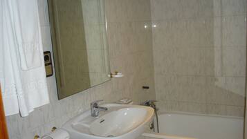 Un baño con lavabo, espejo y bañera.