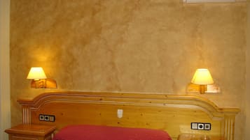 Una camera da letto con una testiera in legno, due comodini e due lampade a parete.