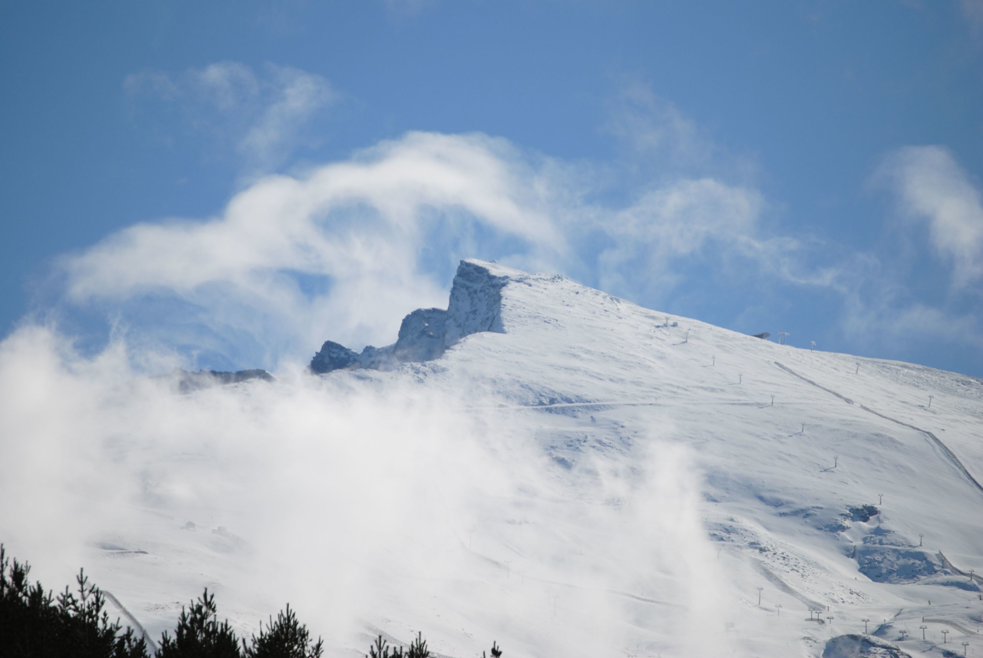 Een met sneeuw bedekte berg met een heldere lucht en wolken.