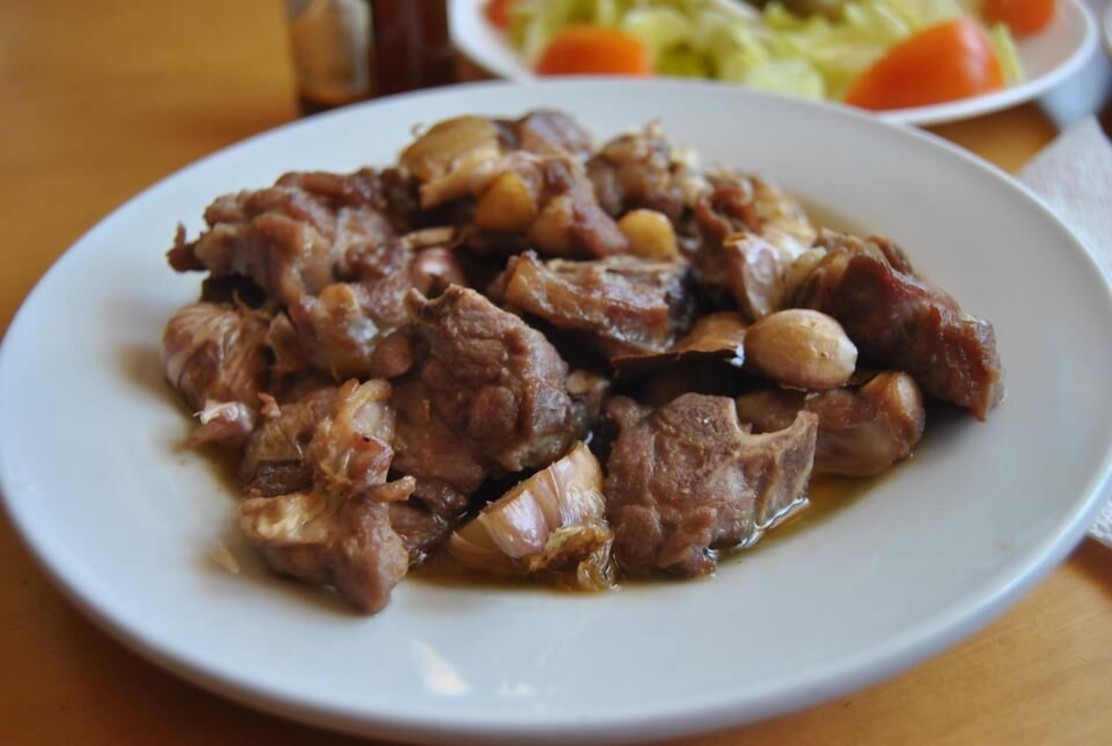 A plate of cooked meat with onions and possibly other vegetables.