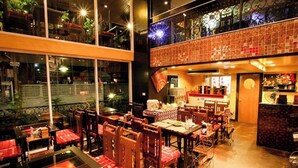 A restaurant with multiple dining tables and chairs, large windows, and a decorative ceiling. - Sabai Sabai @ Sukhumvit Hotel (Bangkok)
