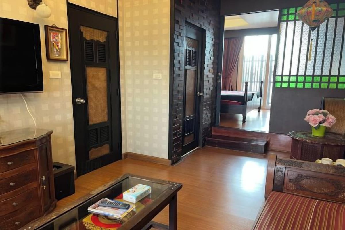 A living room with a wooden coffee table, a sofa, a television, and a door leading to another room.