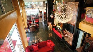 A spacious living area with a red sofa, a fireplace, and a chandelier. - Sabai Sabai @ Sukhumvit Hotel (Bangkok)