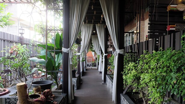 A covered walkway with potted plants and a wooden floor, leading to a building entrance. - Sabai Sabai @ Sukhumvit Hotel (Bangkok)