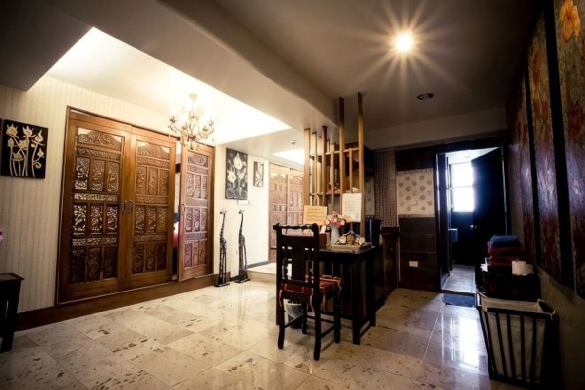 Un pasillo amplio con puerta de madera, un comedor con sillas y un basurero.
