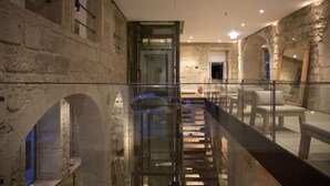 A modern interior with stone walls, a glass railing, and a staircase leading to a higher level. - Hotel Carris Porto Ribeira (Porto)