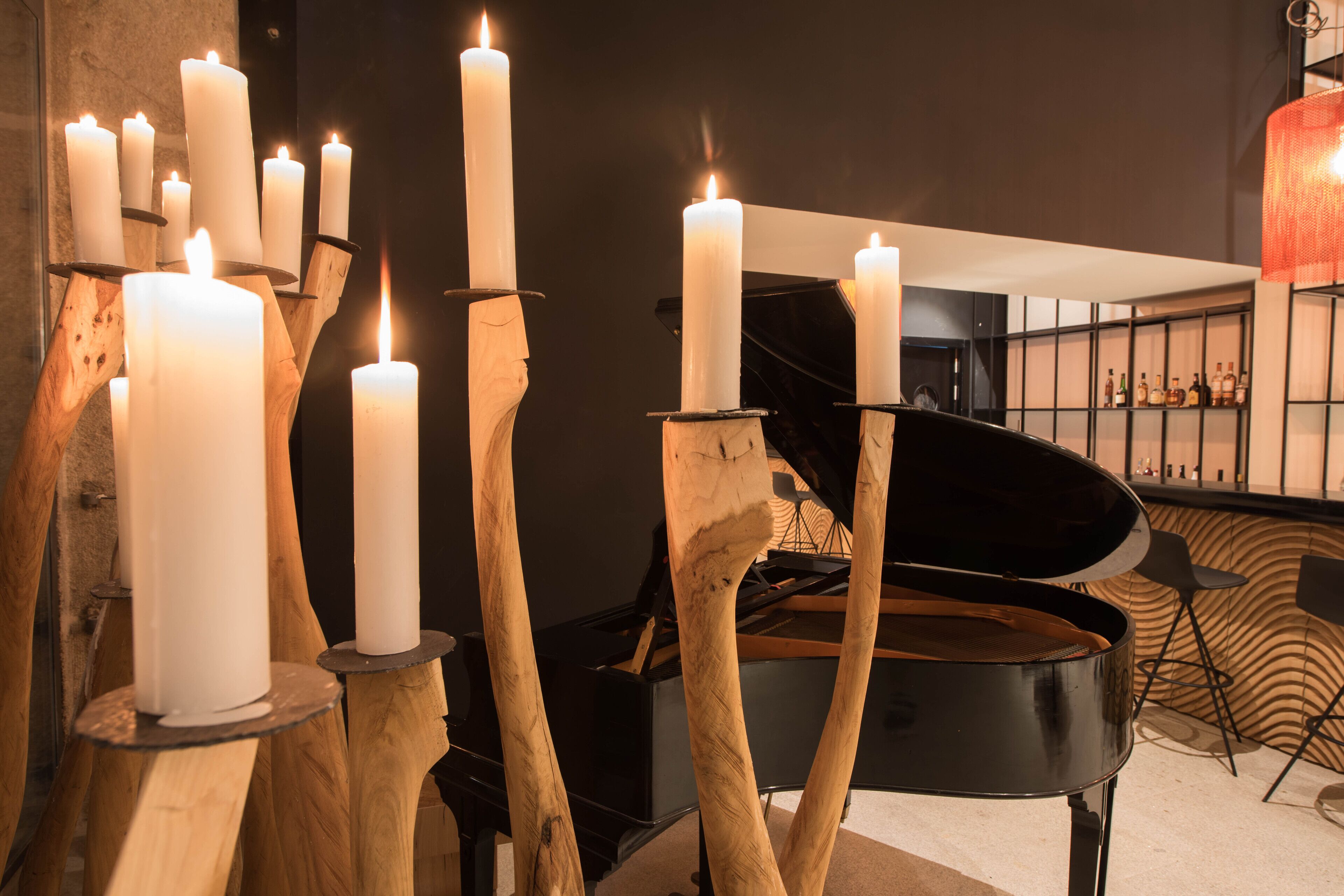 A grand piano in a room with multiple white candles on wooden stands.