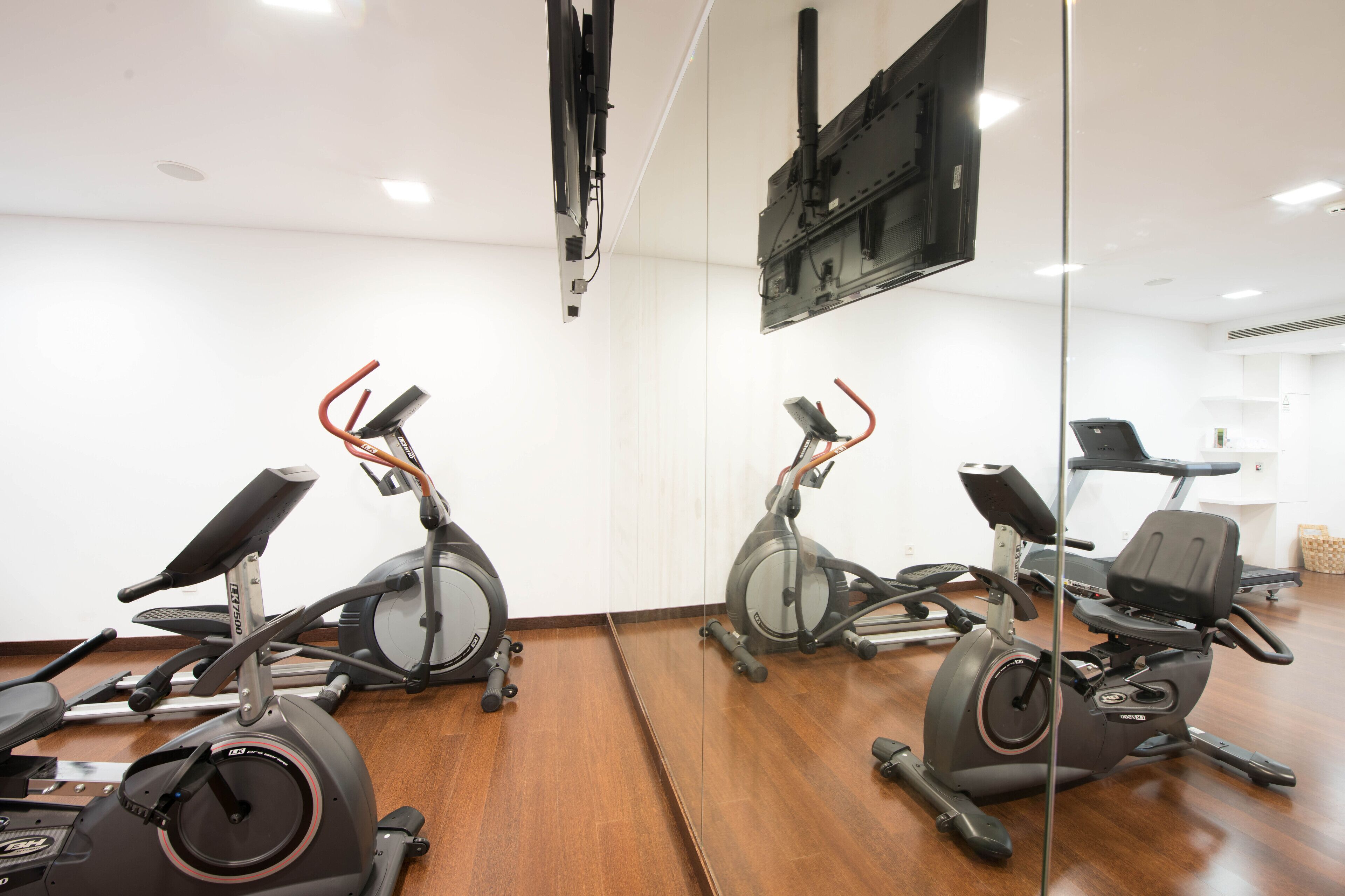 Une salle de sport équipée de plusieurs vélos d’appartement et dotée d’un mur recouvert de miroirs.