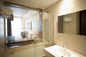 A modern bathroom with a glass shower enclosure, a white sink, and a large mirror.