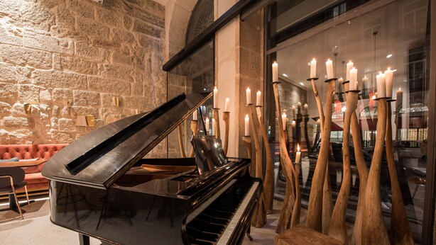 A grand piano in a room with stone walls and a large window. - Hotel Carris Porto Ribeira (Porto)