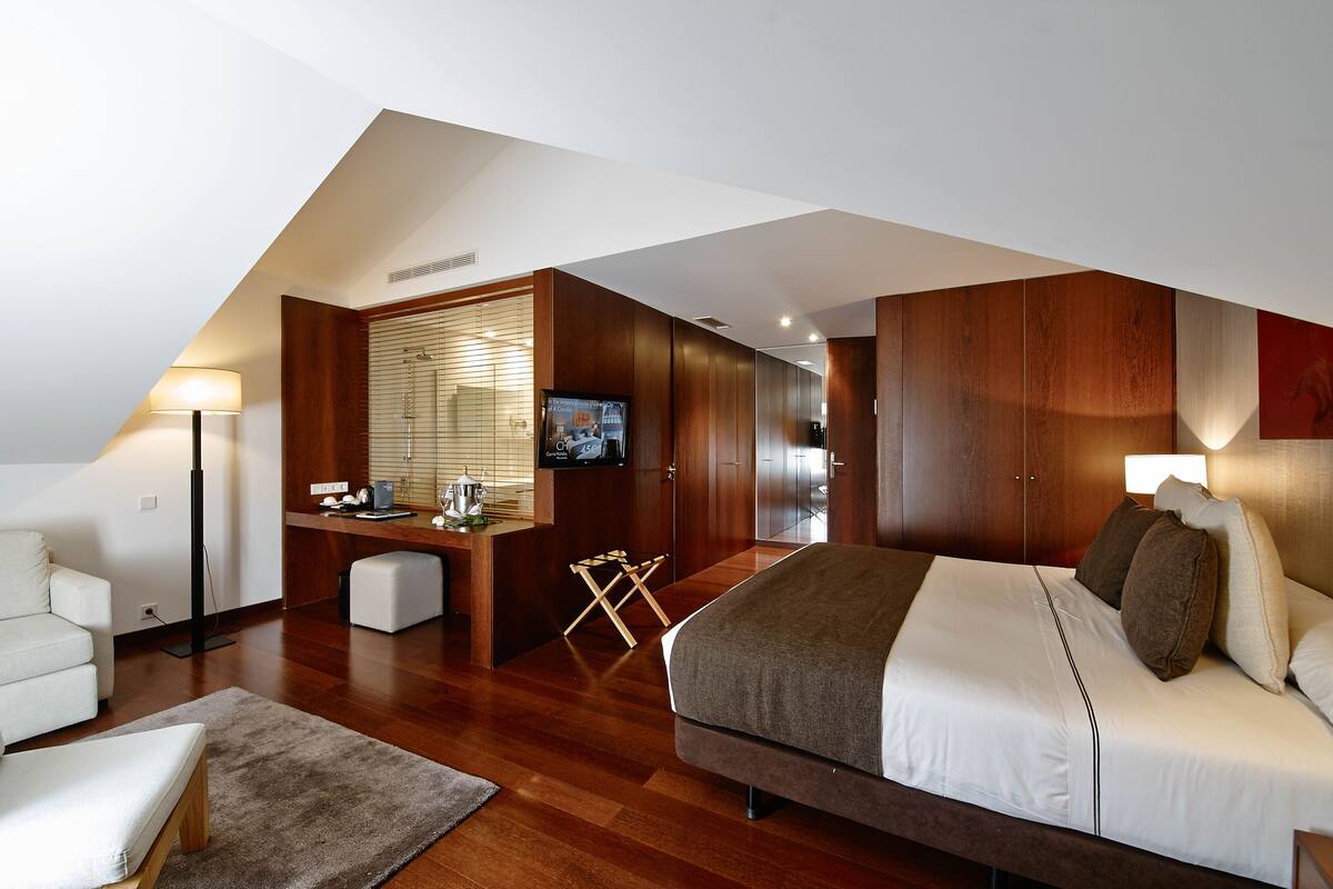 A modern bedroom with a large bed, a desk, and a TV.