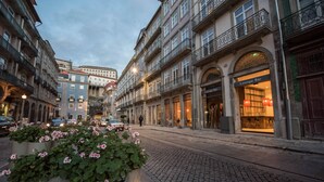 A cobblestone street lined with historic buildings, including a lounge bar with a warm interior and large windows. - Hotel Carris Porto Ribeira (Porto)